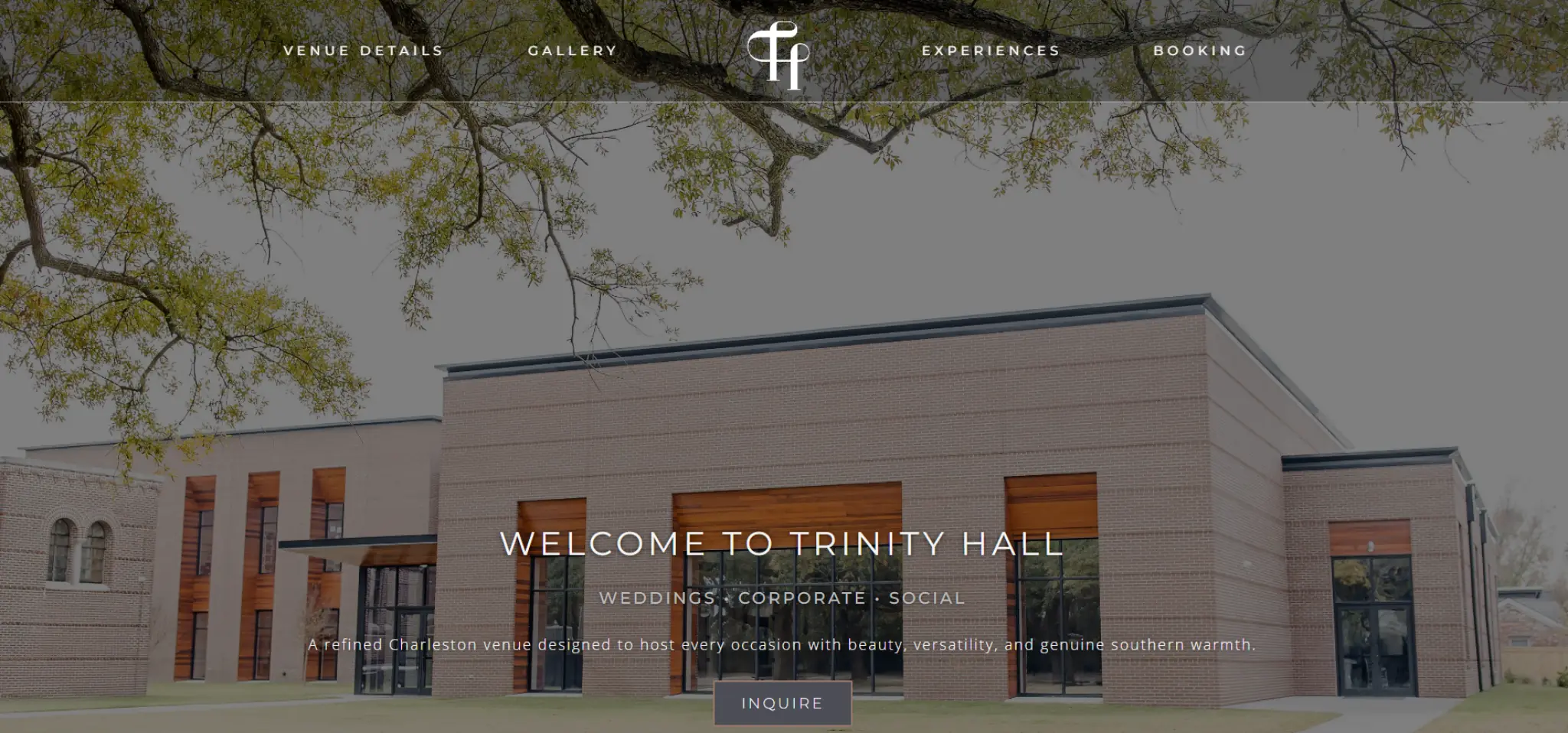 Modern brick building of Trinity Hall with large windows and trees overhead.