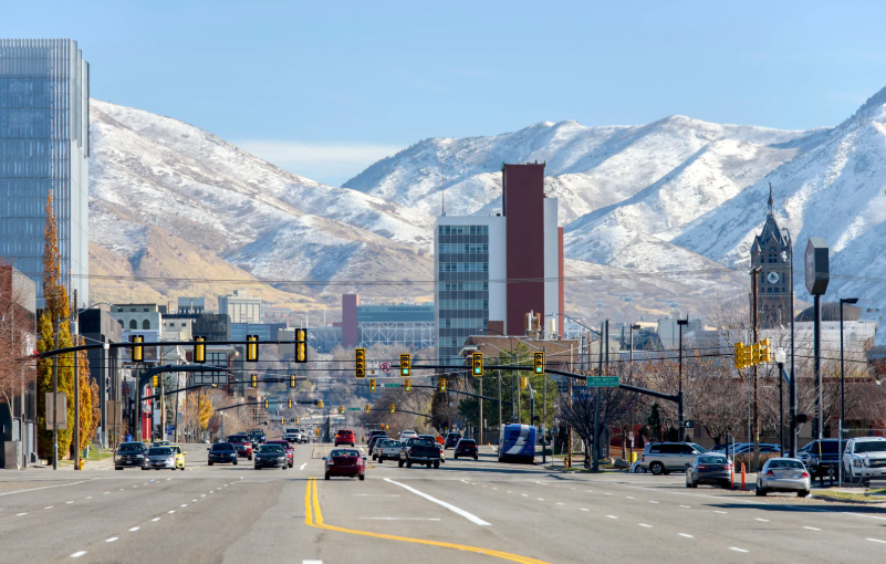 Wide street view of Midvale city center with snow-capped mountains in the background near West Main apartments.