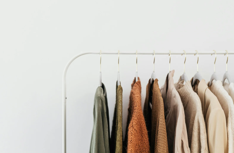 Neutral-toned clothing hanging on a white metal rack, showcasing ample storage and walk-in closet potential at West Main.