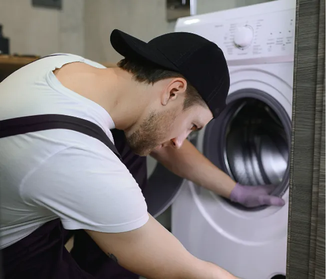 Technician inspecting the open door of a front-loading washing machine.