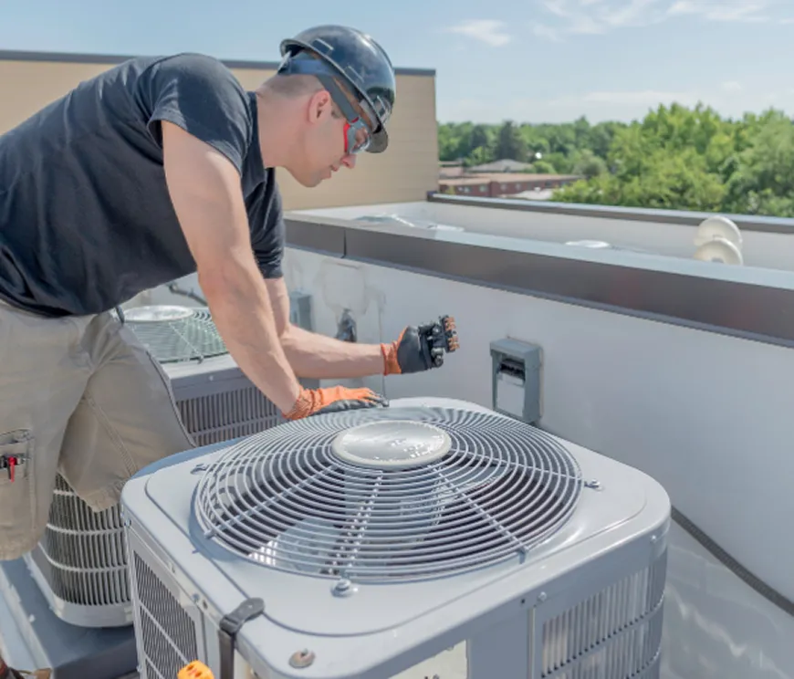 Technician inspecting an HVAC unit on a rooftop.