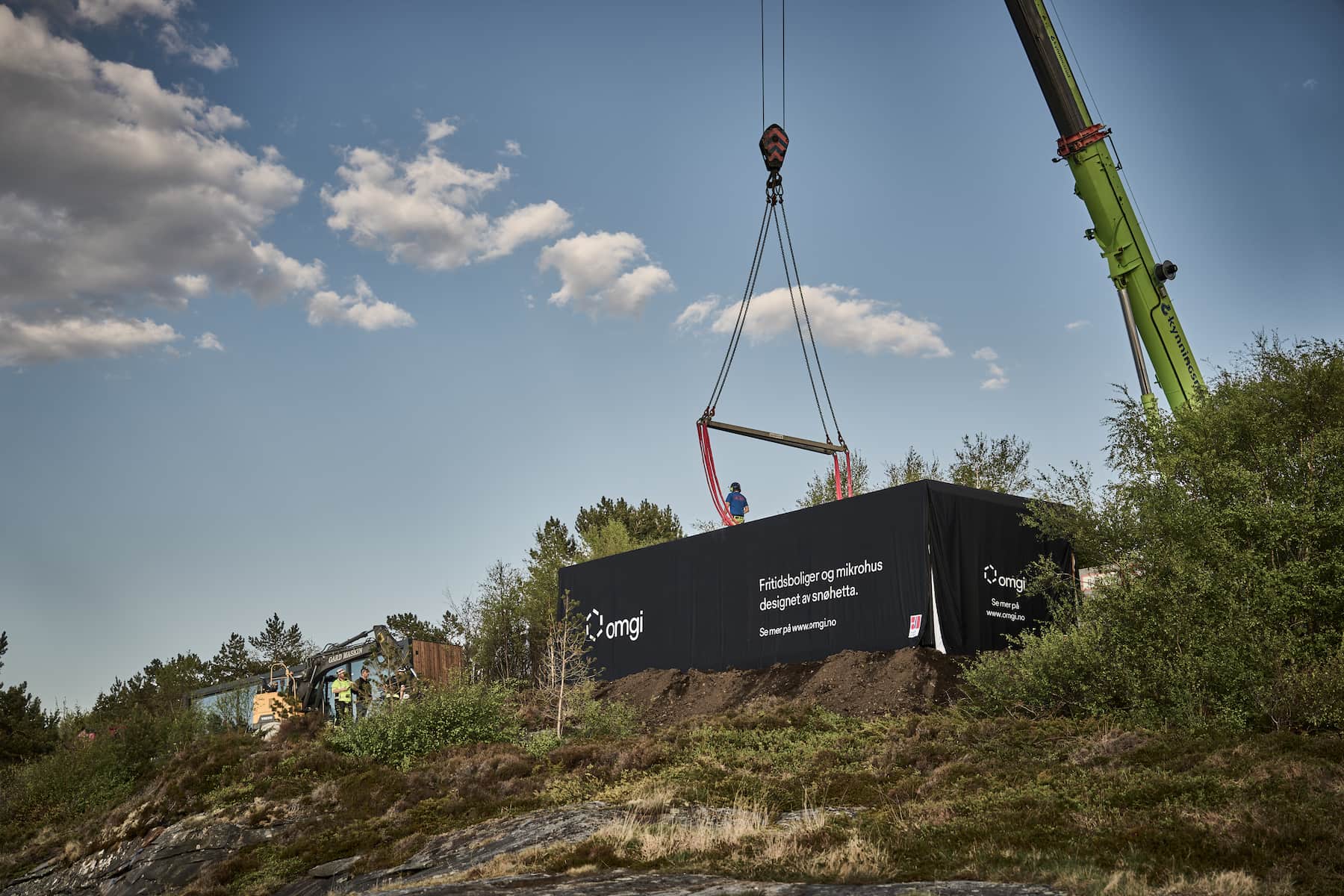 En Omgi hytte leveres med heisekran i skogslandskap