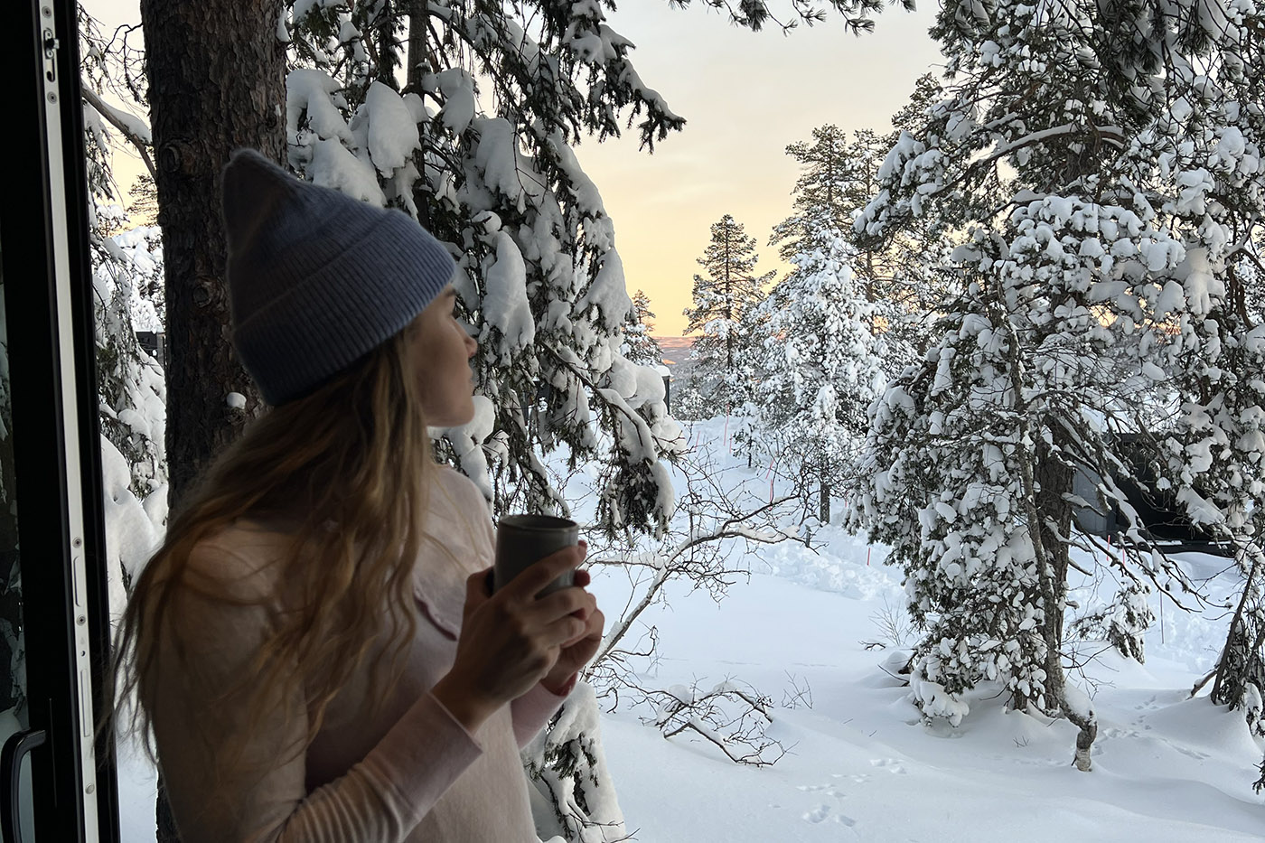 En kvinne skuer utover snødekt landskap iført ullundertøy