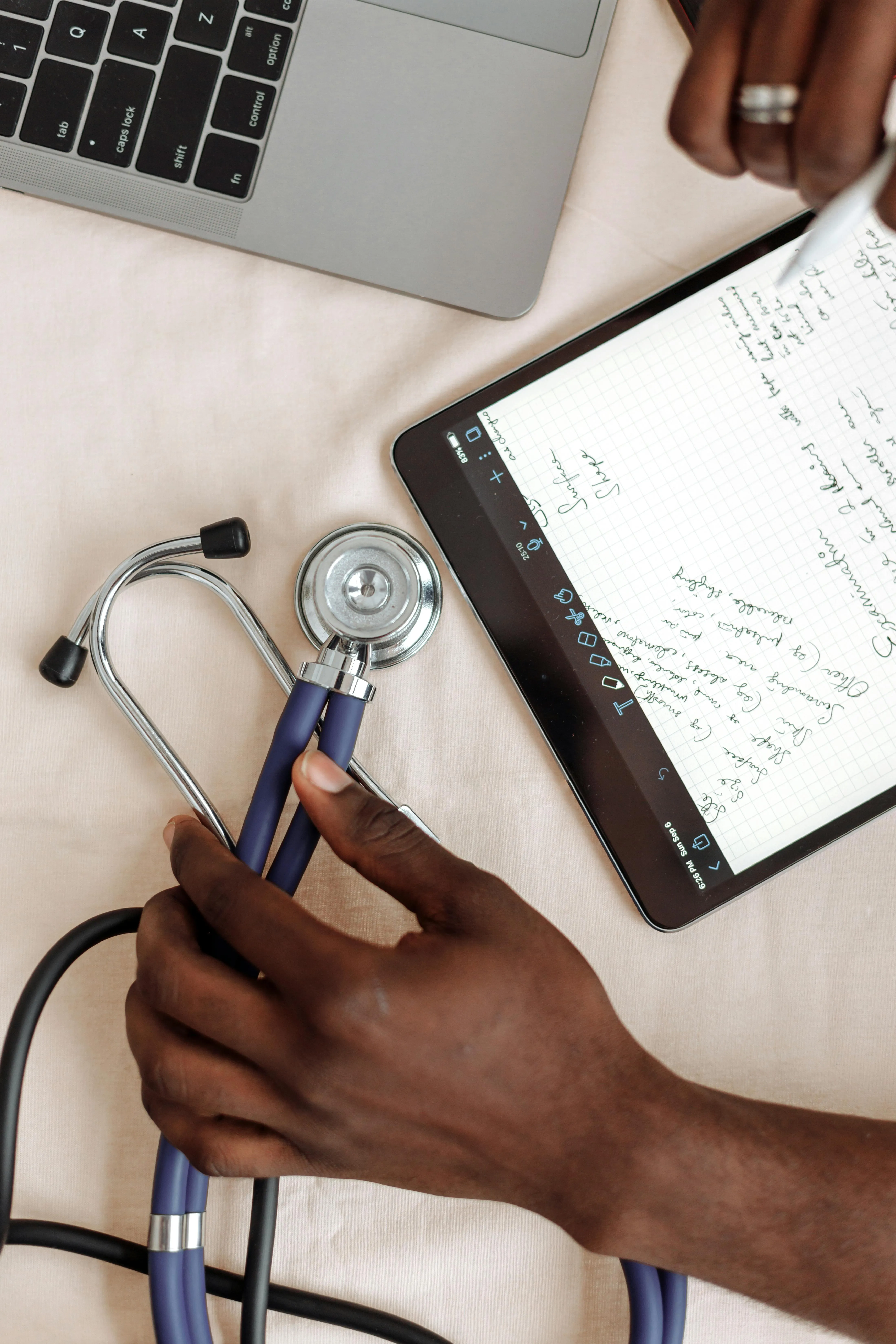 Hand holding a stethoscope beside a notebook