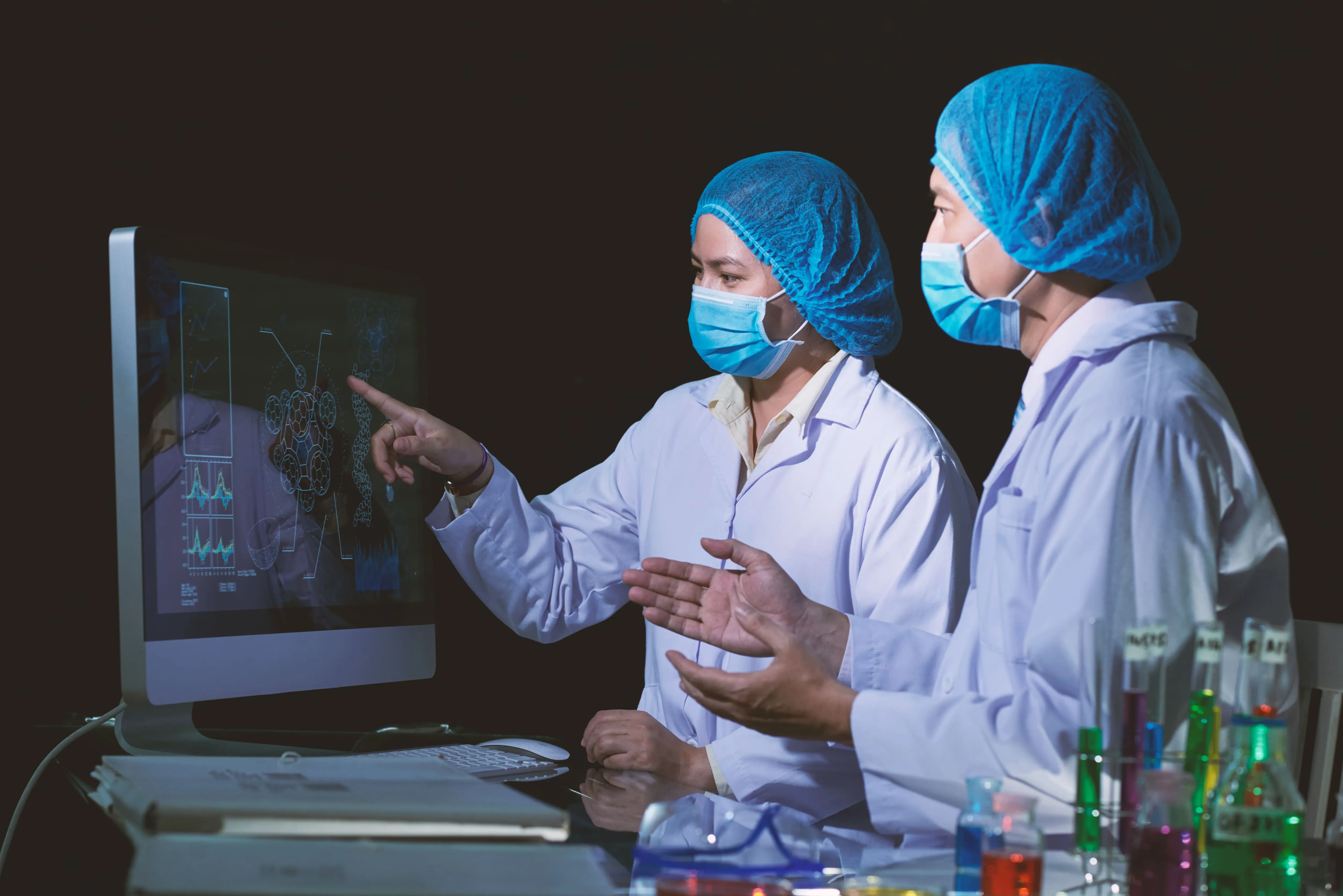 Masked clinicians reviewing results on a monitor