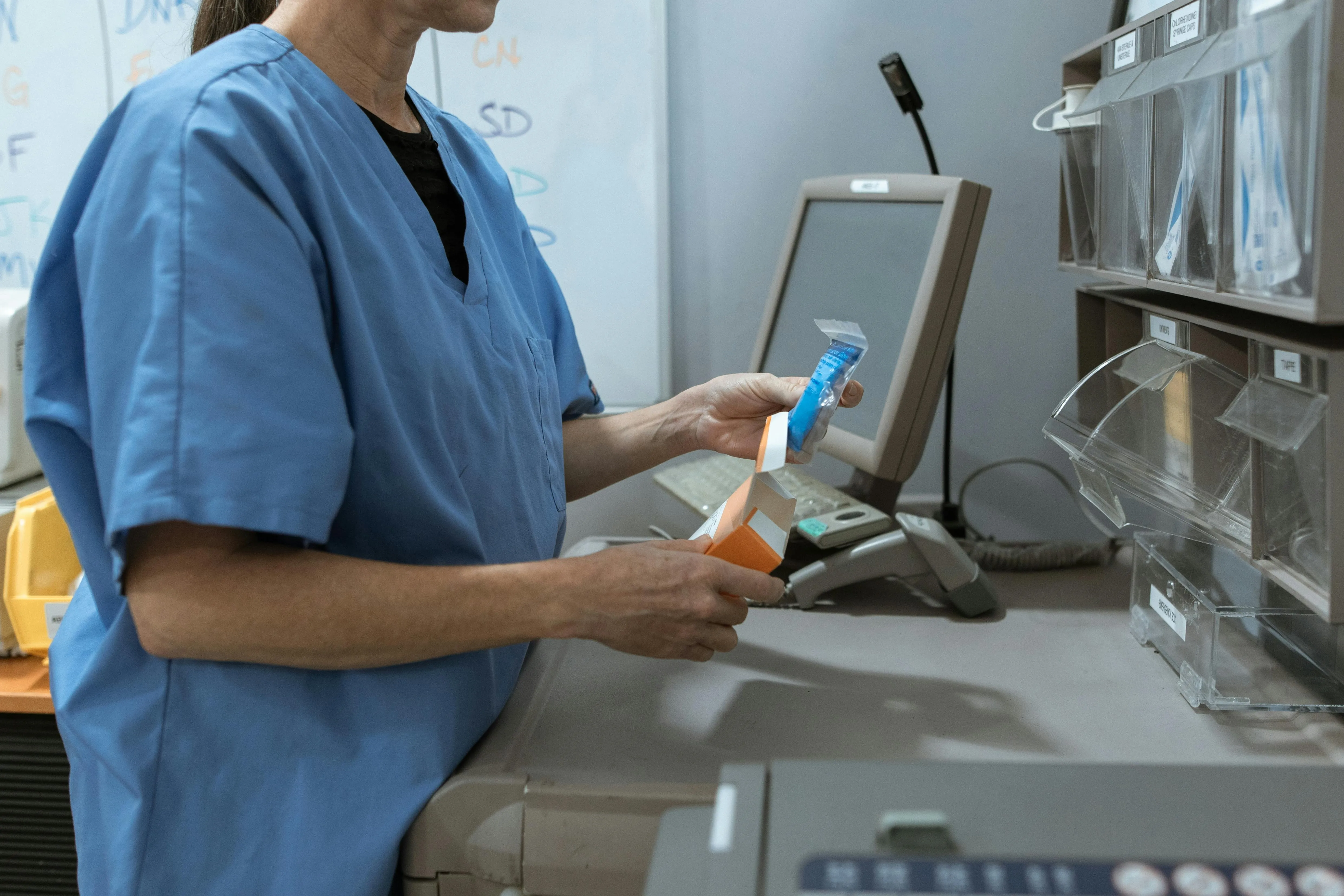 Clinician in scrubs reviewing patient information on a screen