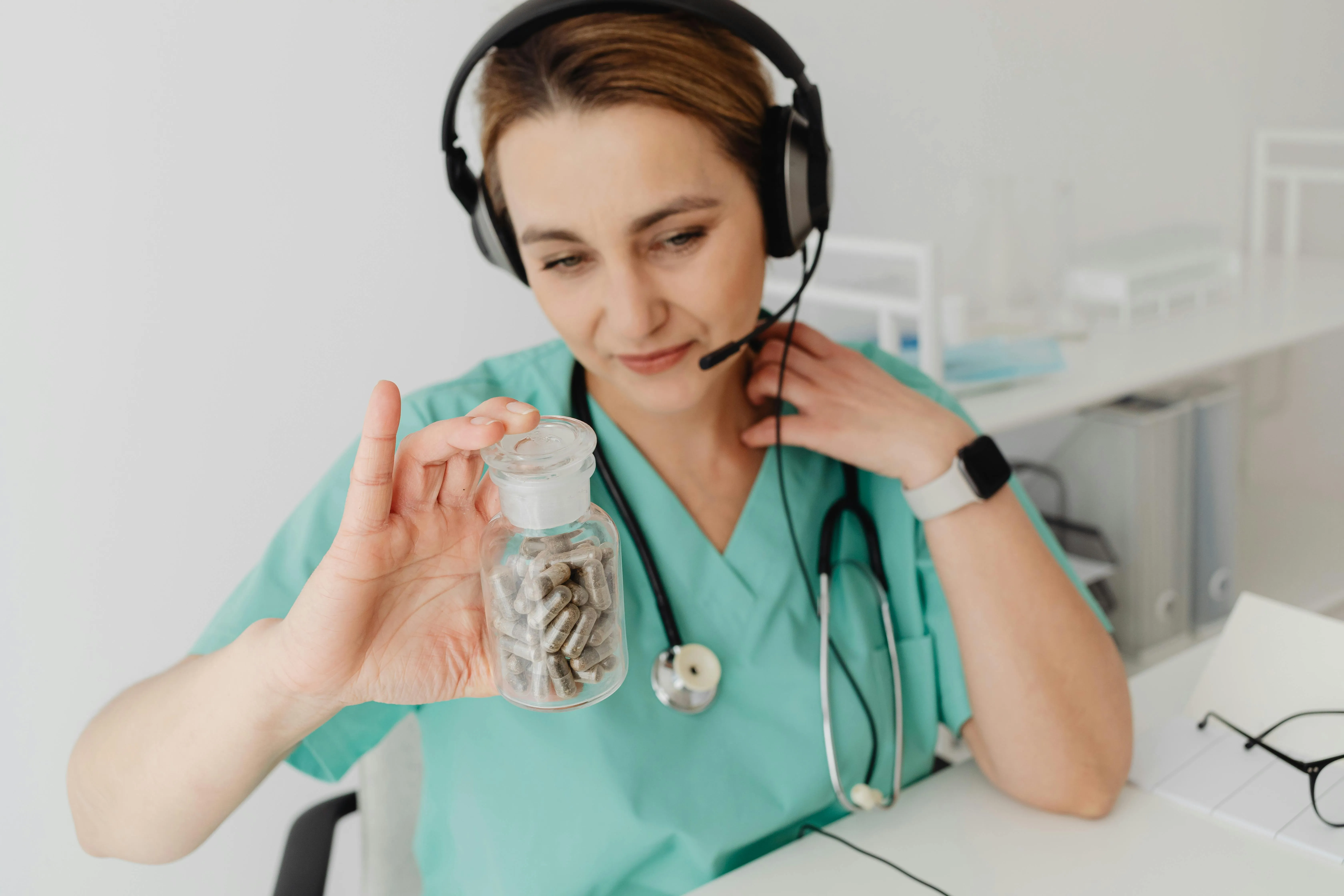 Pharmacist wearing a headset holding a blister pack of tablets