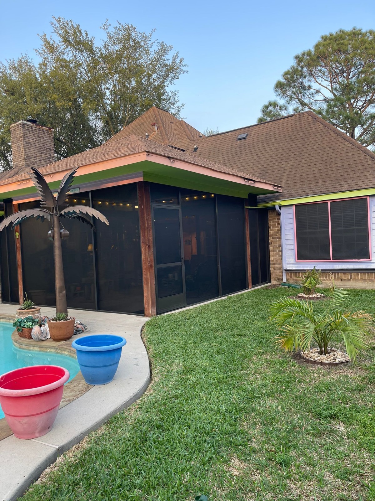 A screened-in porch with green trim and a pool in the backyard of a home.