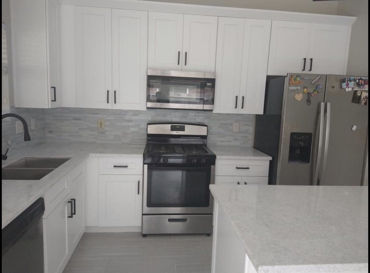 A modern kitchen featuring white cabinetry, stainless steel appliances, and marb