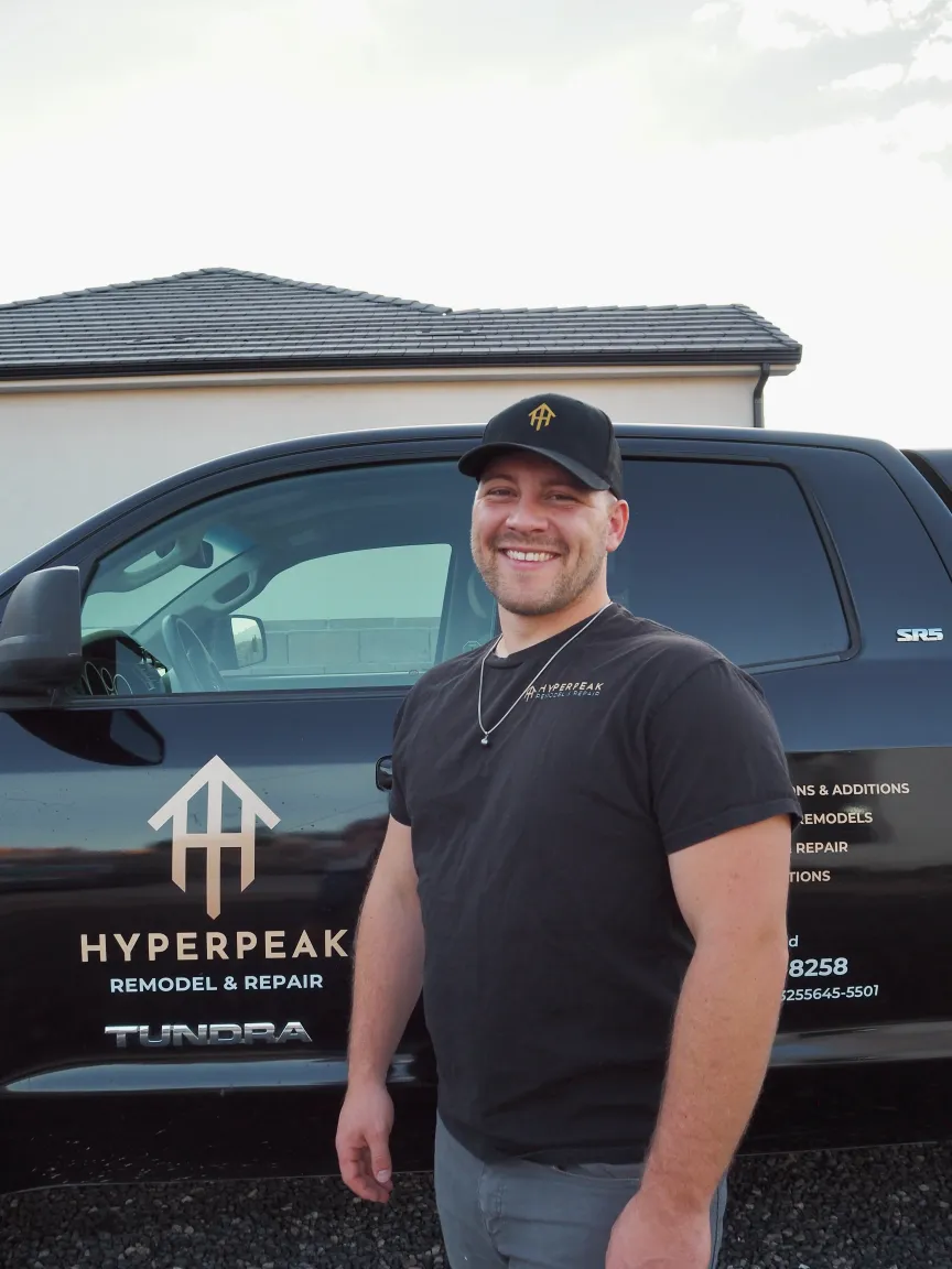Man with logo on hat in front of a black work truck
