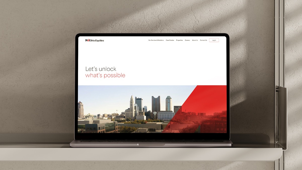 Laptop on a shelf displaying a website with a city skyline and text 'Let’s unlock what’s possible'.