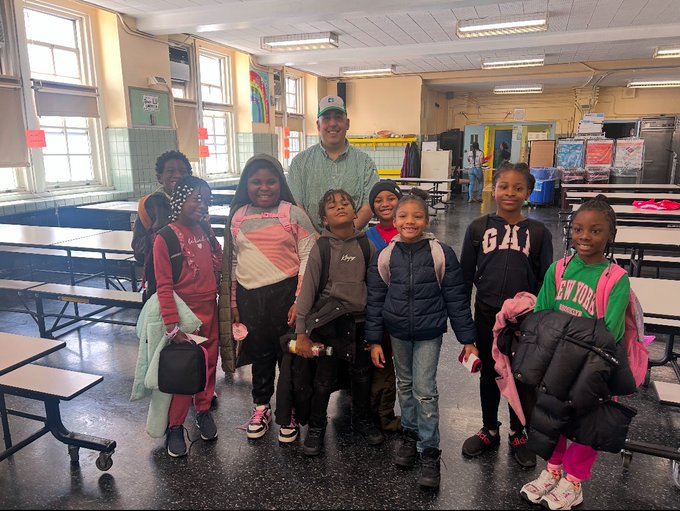 Adult staff member posing with group of students in school cafeteria