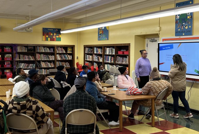 Teachers presenting kindergarten reading lesson to parents in school library