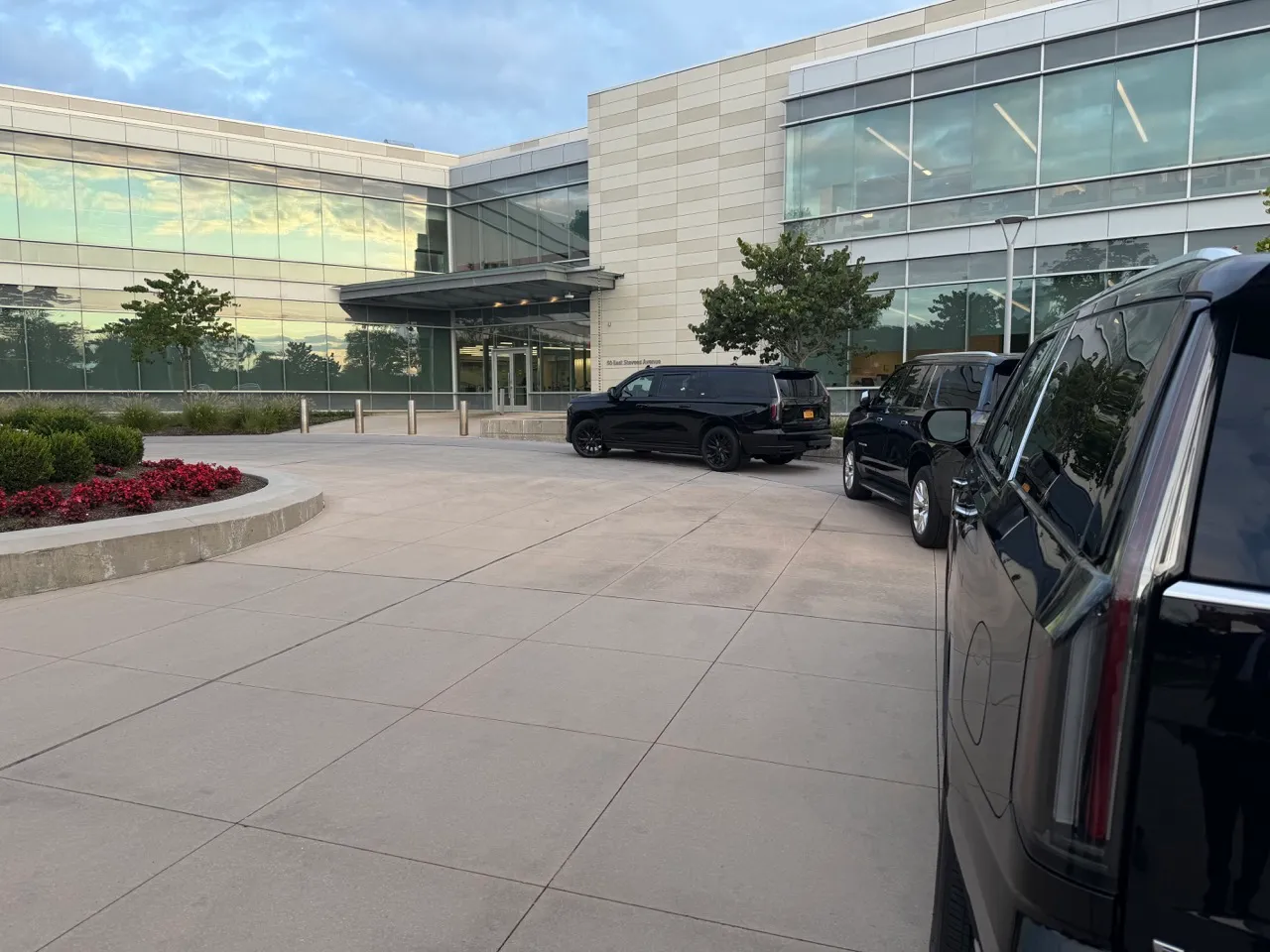 GeronimoLux Cadillac Escalade SUVs waiting at a corporate office entrance