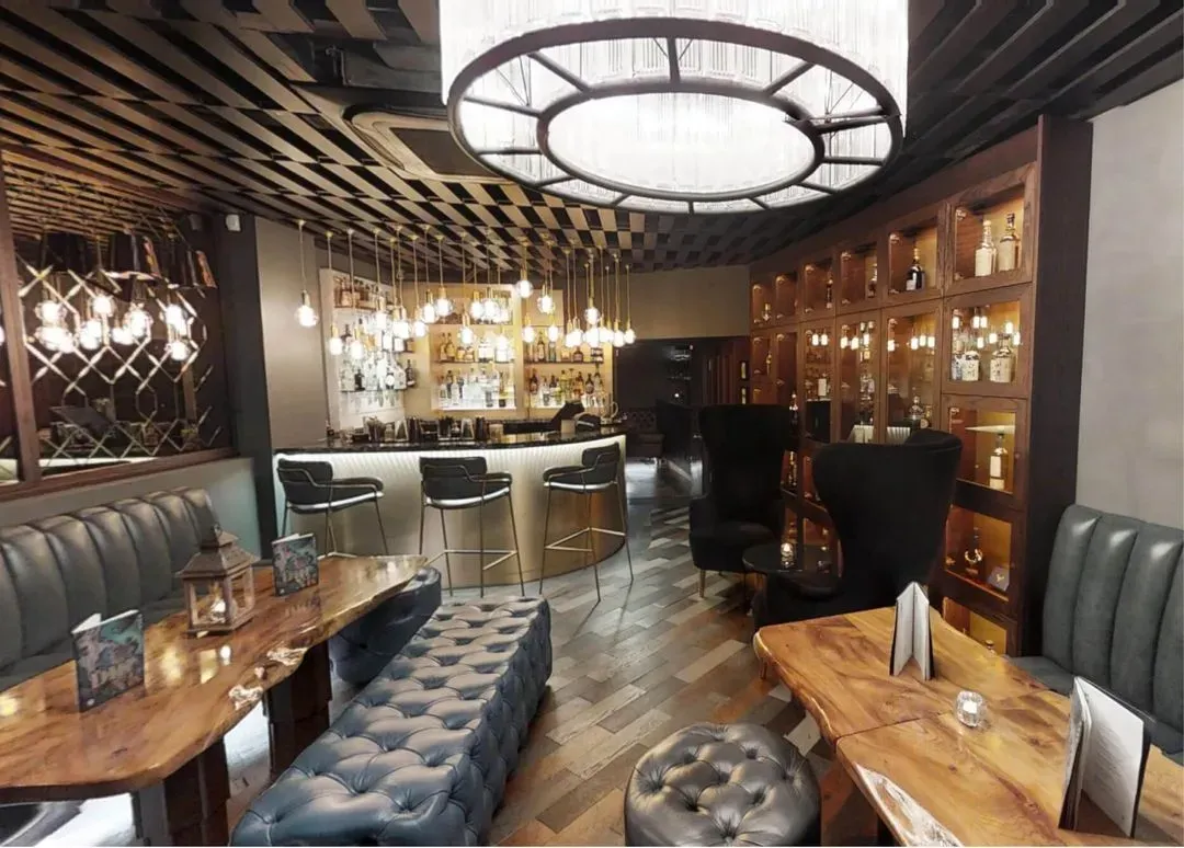  Luxurious bar with leather seats and a grand chandelier hanging from the ceiling.