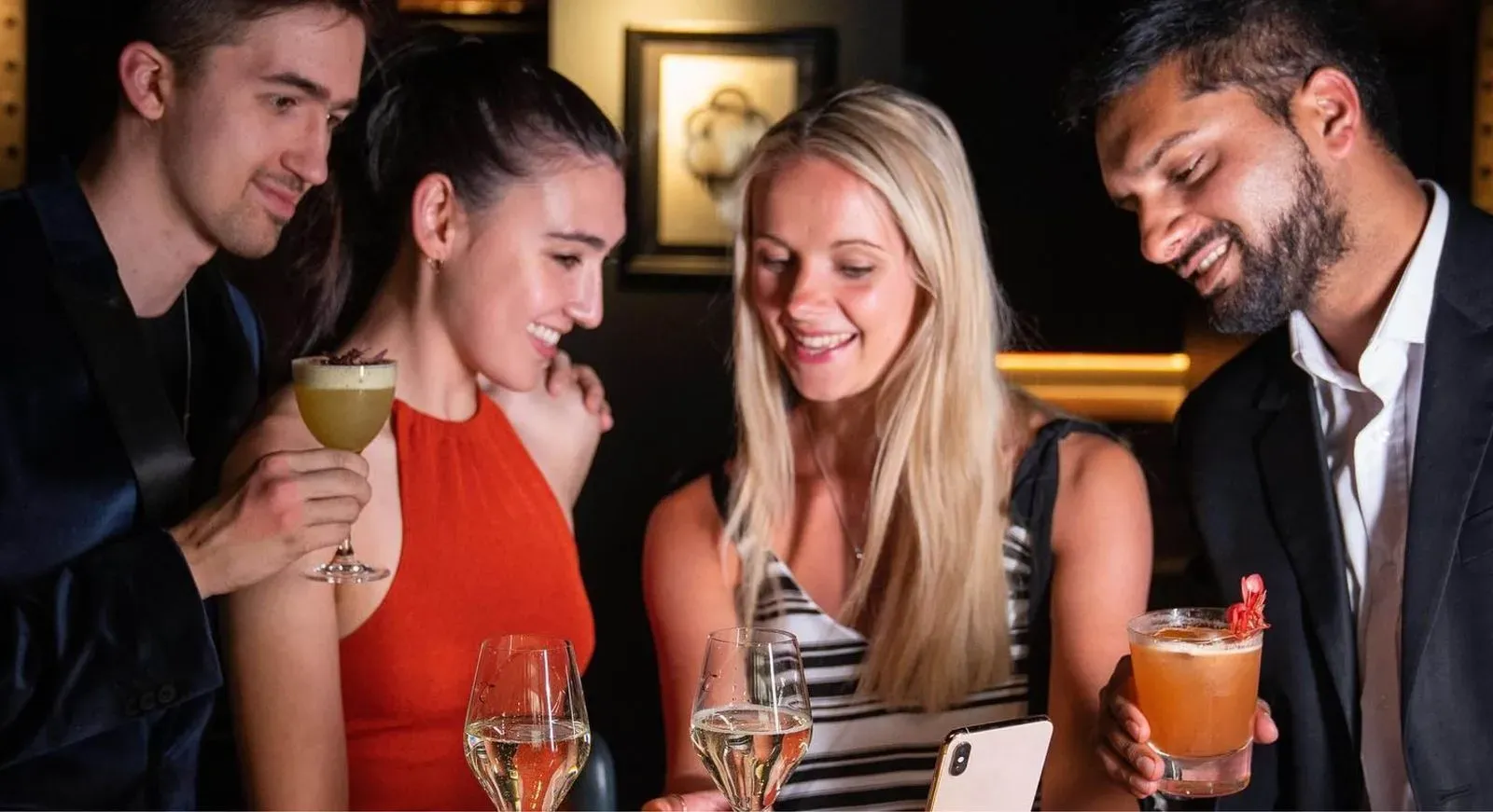 Three individuals happily holding beverages, smiling.