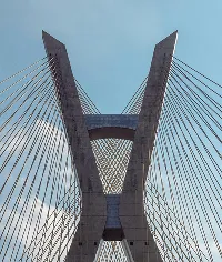 Cable-stayed bridge against a blue sky, concrete pylons with steel cables, modern architecture.