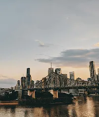 Story Bridge at sunset in Brisbane. City skyline with high-rise buildings and river.