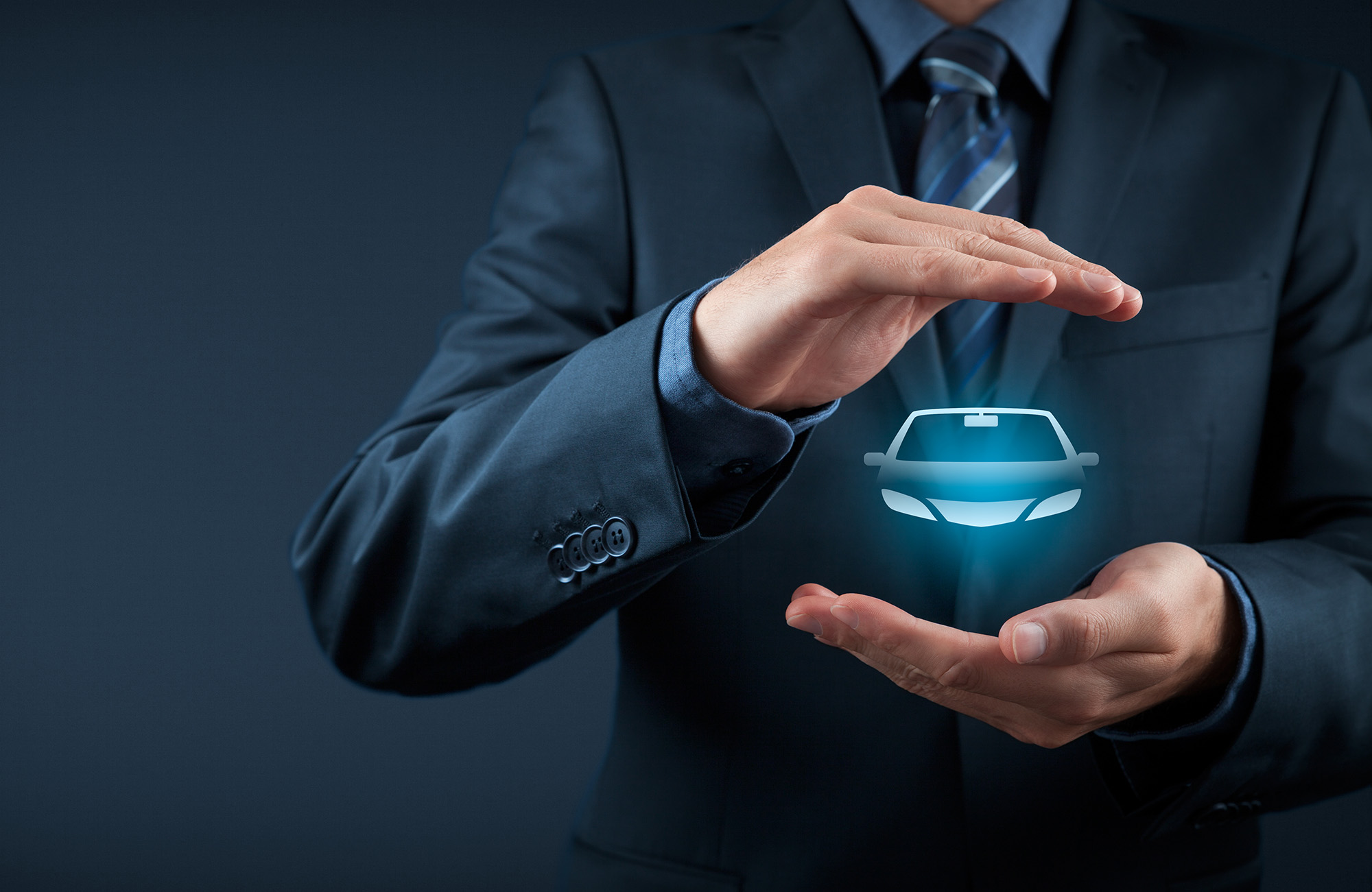 Man in suit with hands framing a glowing car icon, symbolizing car insurance or protection.
