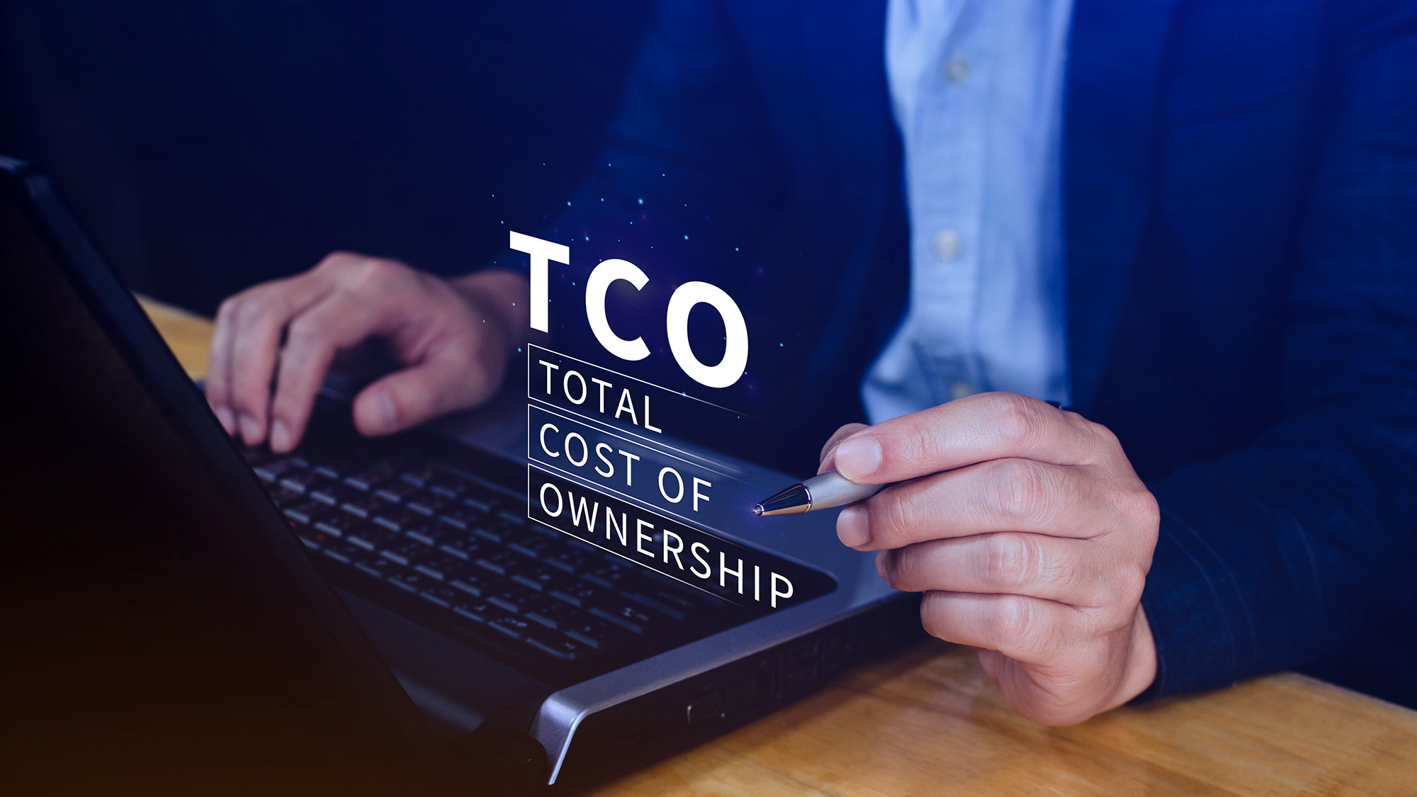 Person using a laptop with the words 'TCO Total Cost of Ownership' digitally displayed above the keyboard.