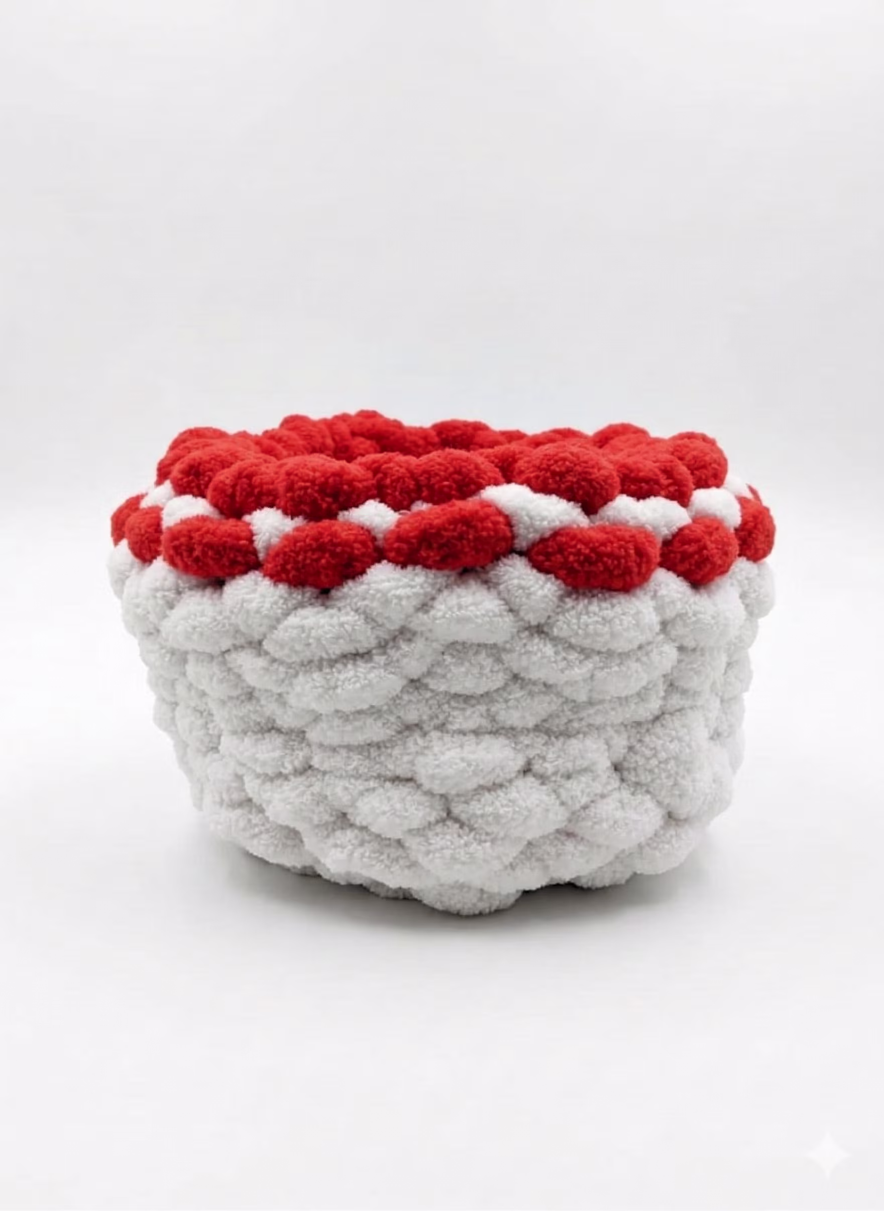 Belo-crvena ručno pletena korpa od plišane vunice izolovana na čistoj beloj pozadini.