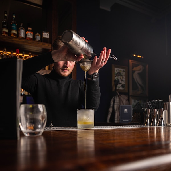 a man pouring a drink at a bar