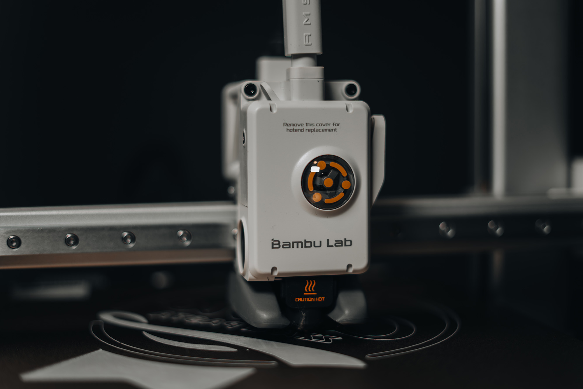 Nahaufnahme des Druckkopfs einer Bambu Lab 3D-Druckmaschine beim Drucken auf der Bauplatte.