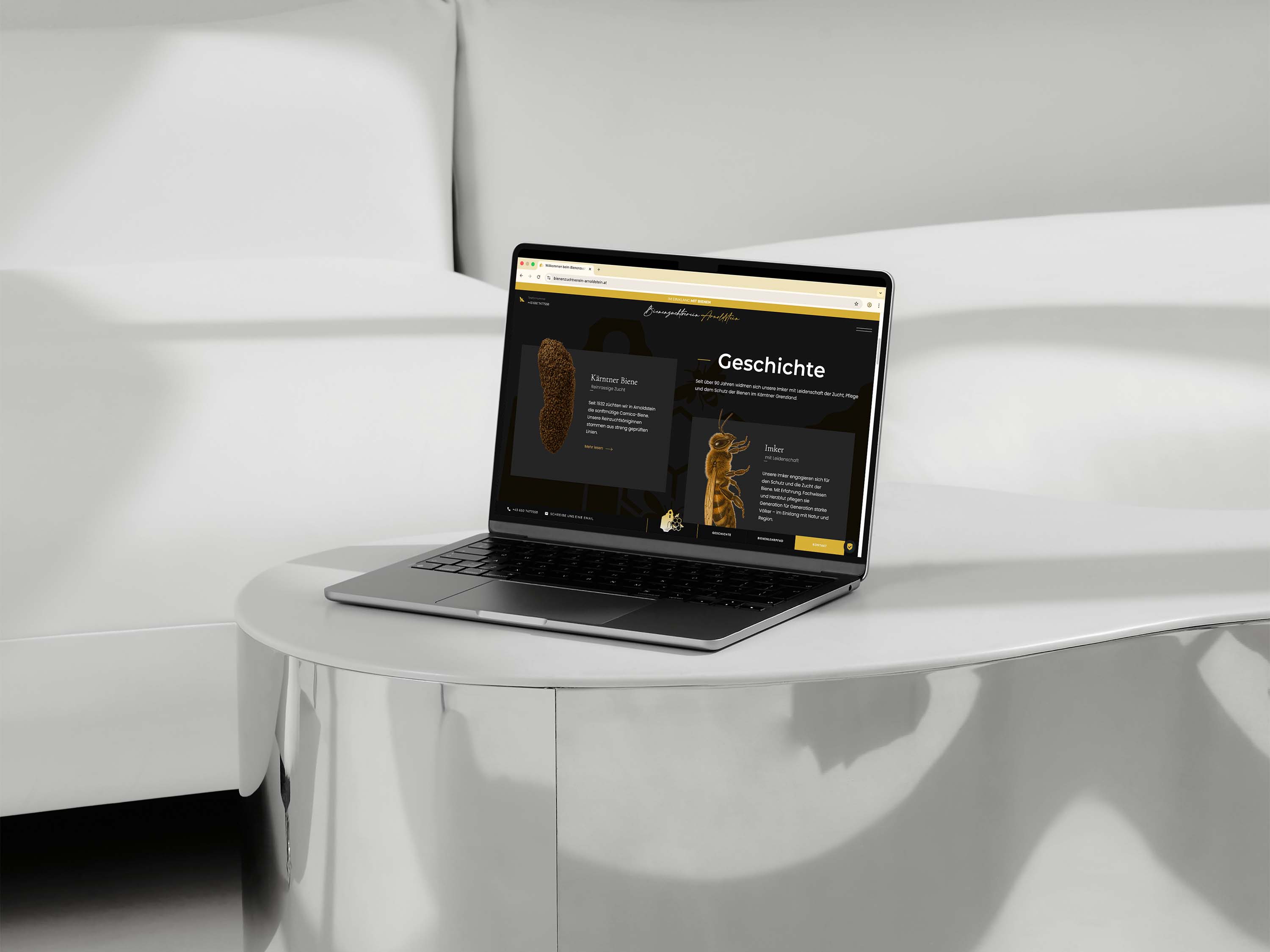 Laptop auf einem weißen, runden Tisch vor einem weißen Sofa, Bildschirm zeigt eine Webseite über Bienen mit dem Titel Geschichte.
