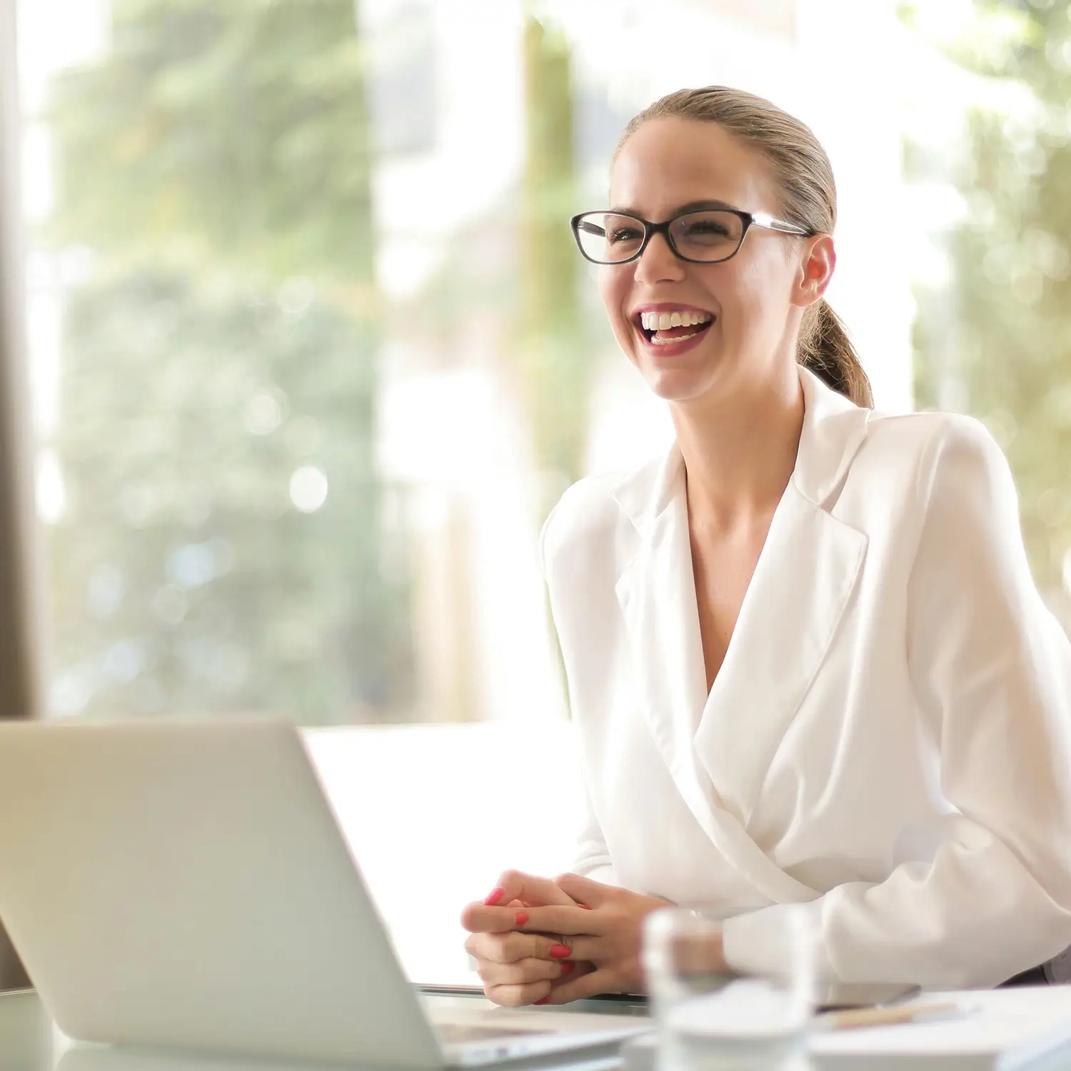 Zufriedene Mitarbeitende dank moderner IT-Benefits: Eine Geschäftsfrau im Büro nutzt einen Laptop von DVICE – dem kostenneutralen Mitarbeiter-PC-Programm der JobRad Gruppe zur Gewinnung von Talenten.