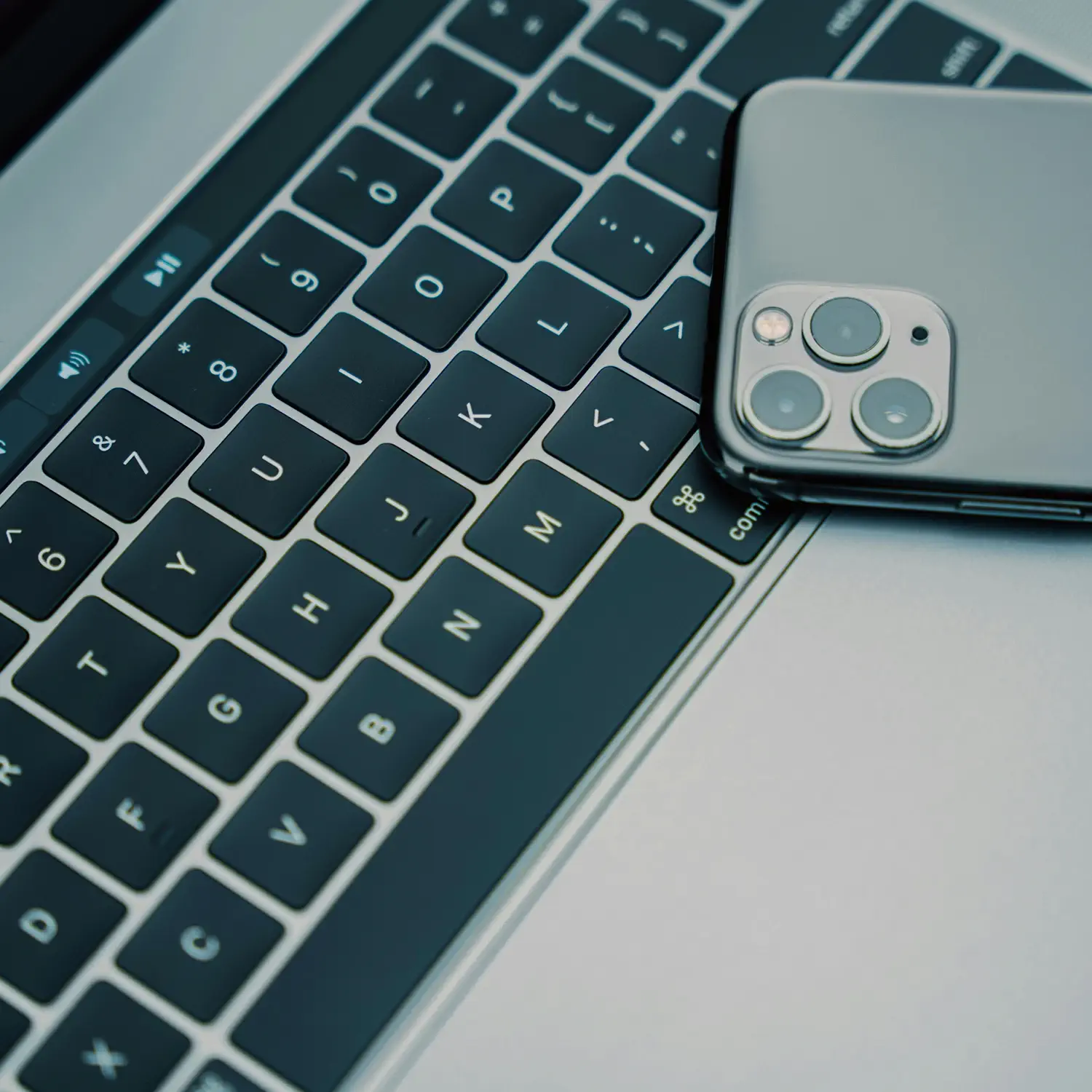 Modernste IT-Hardware im Verbund: Ein iPhone liegt auf einem MacBook von DVICE – das Mitarbeiter-PC-Programm der JobRad Gruppe ermöglicht die nahtlose Integration von mobilen und stationären Geräten für produktives Arbeiten.