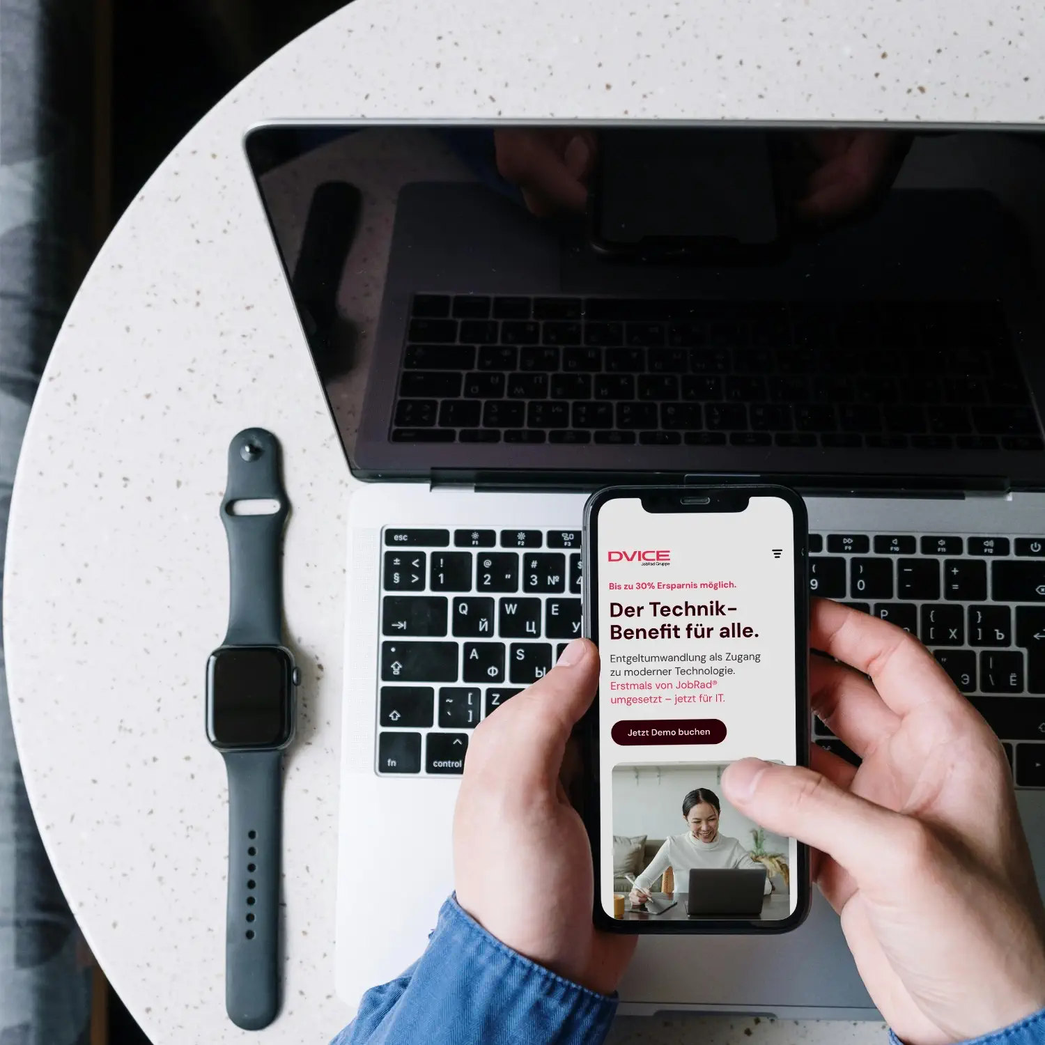 Der Technik-Benefit für alle: Ein Smartphone zeigt die DVICE Landingpage der JobRad Gruppe über einem MacBook – IT-Leasing per Entgeltumwandlung für moderne Unternehmen und Mitarbeitende.