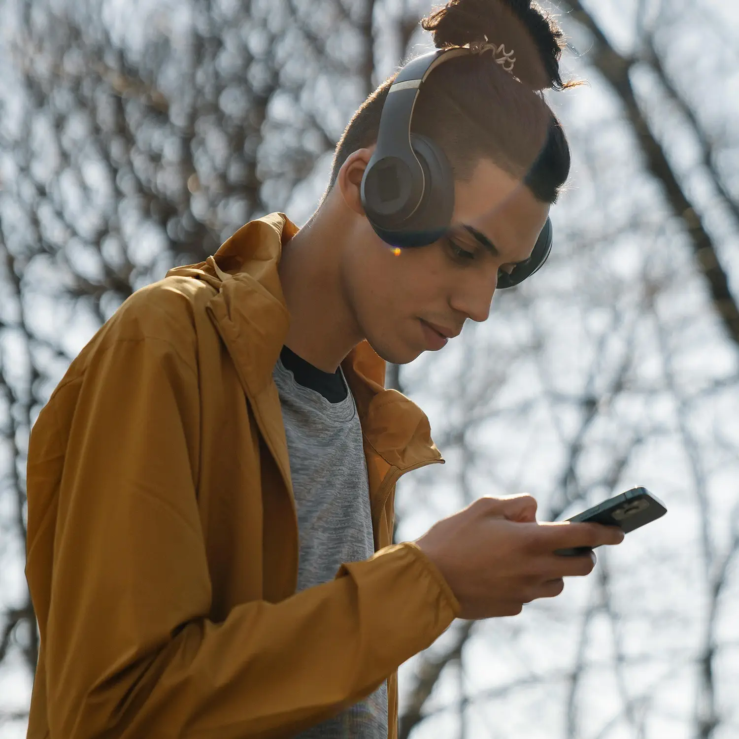 Moderner Technik-Lifestyle mit DVICE: Ein junger Mann nutzt Kopfhörer und Smartphone privat im Freien – ermöglicht durch das Mitarbeiter-PC-Programm der JobRad Gruppe mit attraktiven Steuervorteilen.