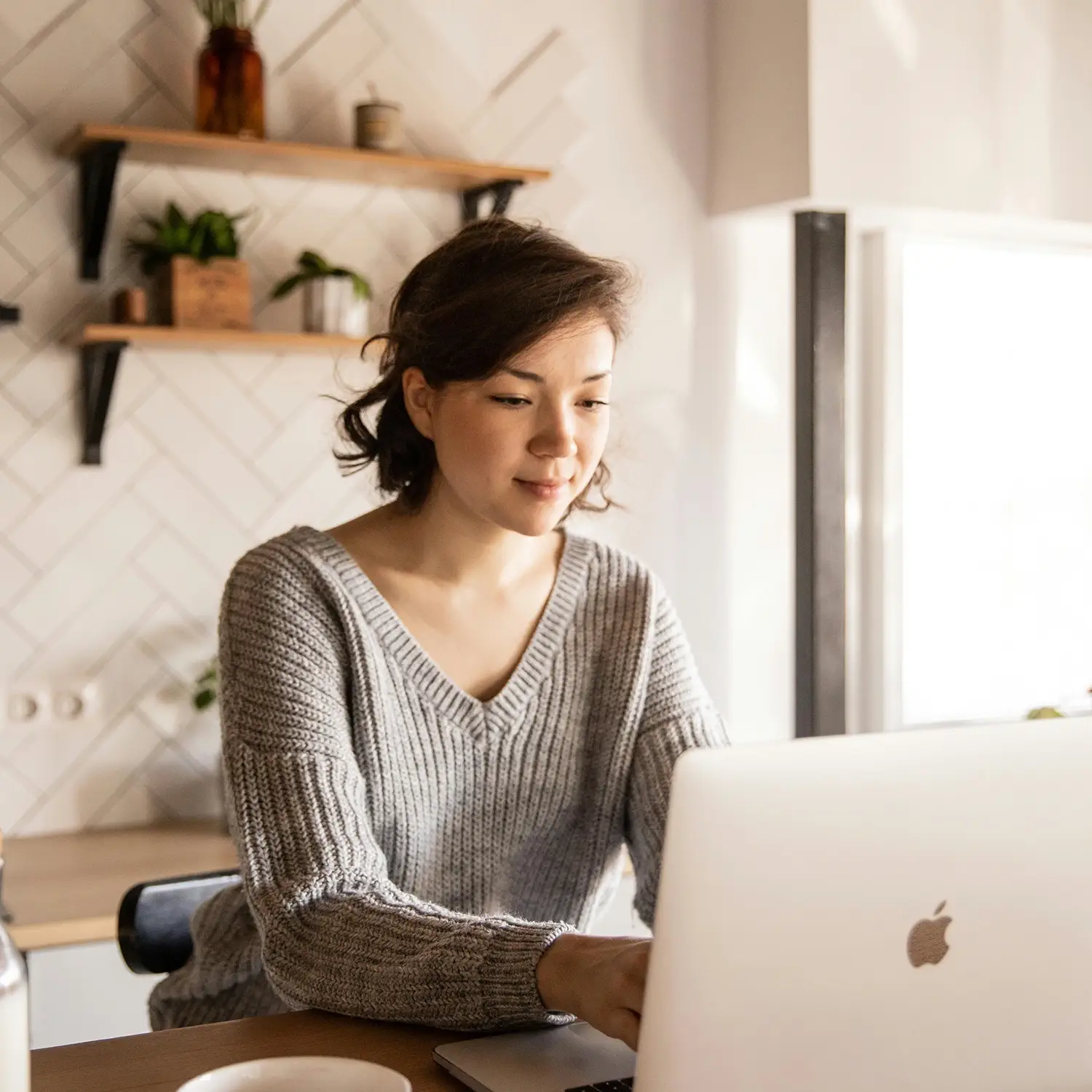 Professionelles Homeoffice mit DVICE: Eine Frau arbeitet an einem MacBook – das digitale Mitarbeiter-PC-Programm (MPP) der JobRad Gruppe ermöglicht den Zugang zu modernster IT-Hardware als Benefit mit bis zu 30 % Ersparnis.