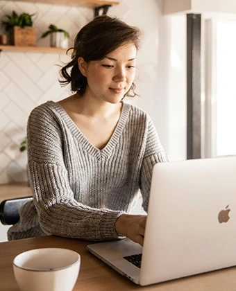 Professionelles Homeoffice mit DVICE: Eine Frau arbeitet an einem MacBook – das digitale Mitarbeiter-PC-Programm (MPP) der JobRad Gruppe ermöglicht den Zugang zu modernster IT-Hardware als Benefit mit bis zu 30 % Ersparnis.