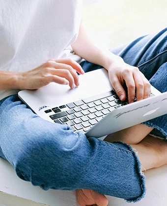 Flexibles Arbeiten und attraktive Privatnutzung: Eine Frau nutzt ein MacBook auf dem Schoß – das digitale Mitarbeiter-PC-Programm (MPP) von DVICE und der JobRad Gruppe bietet modernste IT-Hardware einfach per Gehaltsumwandlung.