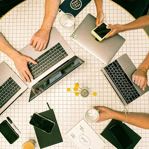 Kollaboration und Mitarbeiterzufriedenheit durch moderne IT: Ein Team arbeitet gemeinsam mit Laptops und Smartphones von DVICE – der Technik-Benefit ohne Mehraufwand für Unternehmen zur Stärkung der Arbeitgeberattraktivität.