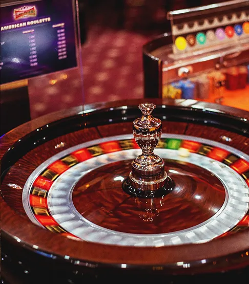 Close-up of a roulette wheel spinning with blurred colored pockets and a metal spindle in the center.