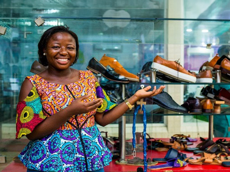 African lady standing in front of a shoe stall