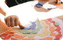 Child making a rainbow with pieces of paper