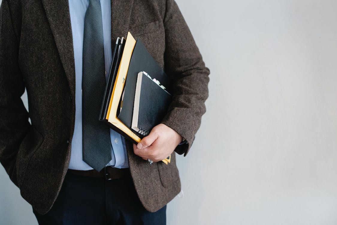 Free Crop unrecognizable office worker standing with papers in hand Stock Photo