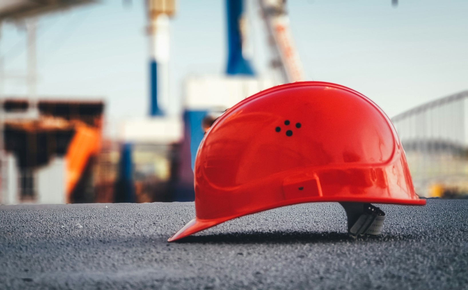 Red hard hat against a construction site backdrop.