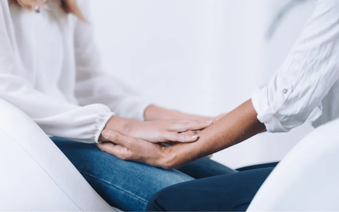 a person sitting on a couch holding another person's hand