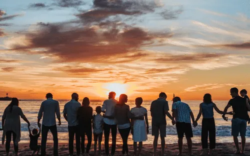 several people standing together watching the sunset on the seashore