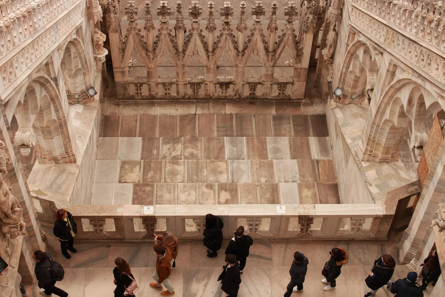 A photograph of people walking through the Duomo di Milano from a high vantage point. 