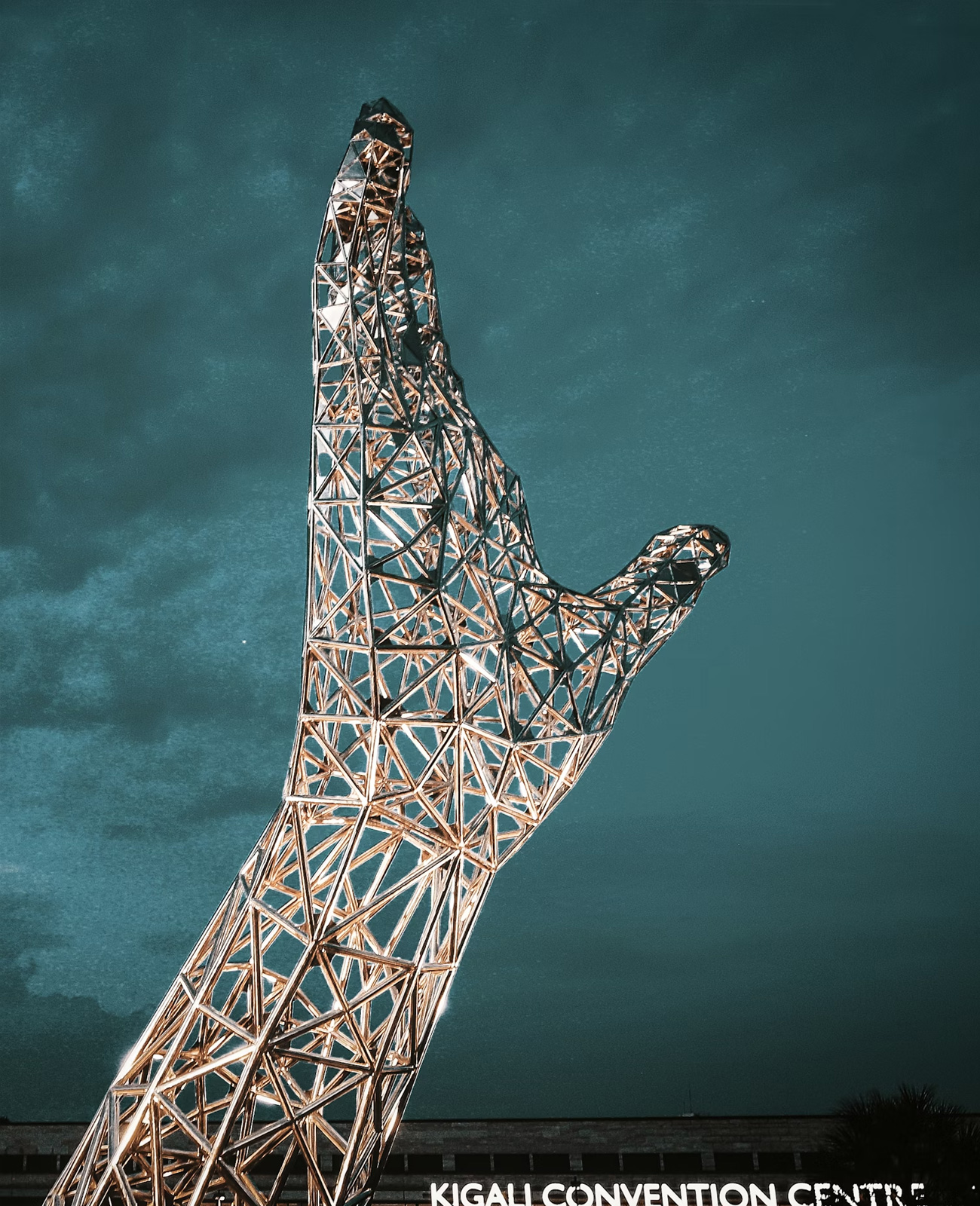 Metallic wireframe sculpture of an outstretched hand against a twilight sky.