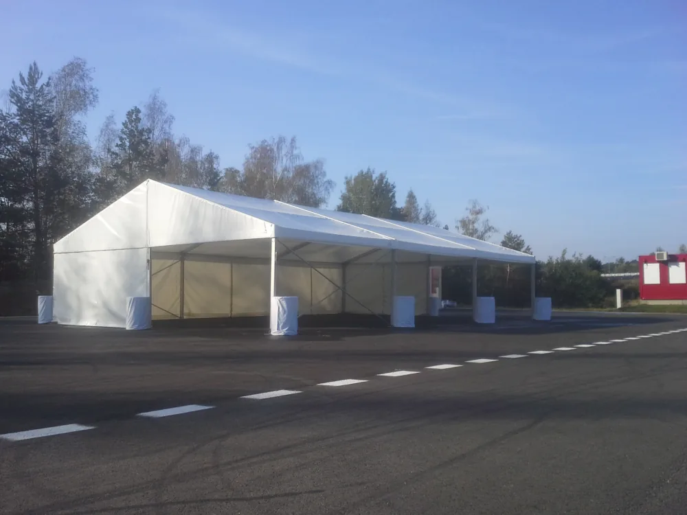 Nový párty stan 10x45 m s plným bílým opláštěním a zátěžovými sudy na parkovišti — Berger Group
