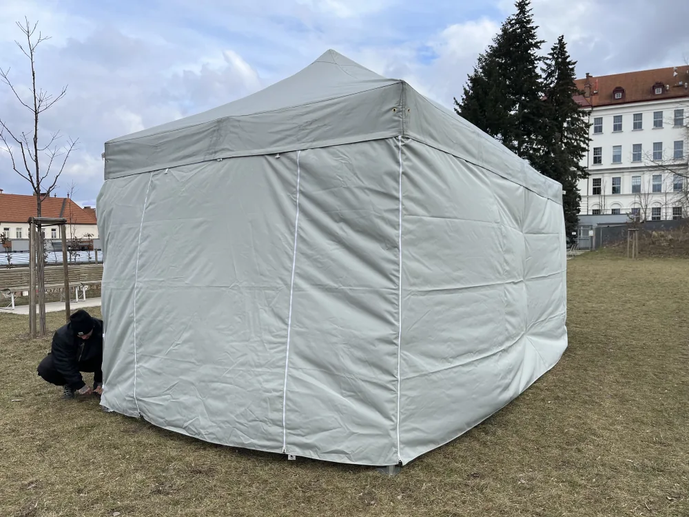 Nůžkový stan 3x6 m šedý s bočními stěnami během montáže na trávníku