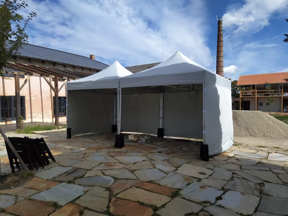 Šedý nůžkový stan 5×5 m se bočními stěnami na zahradě – pohled ze strany