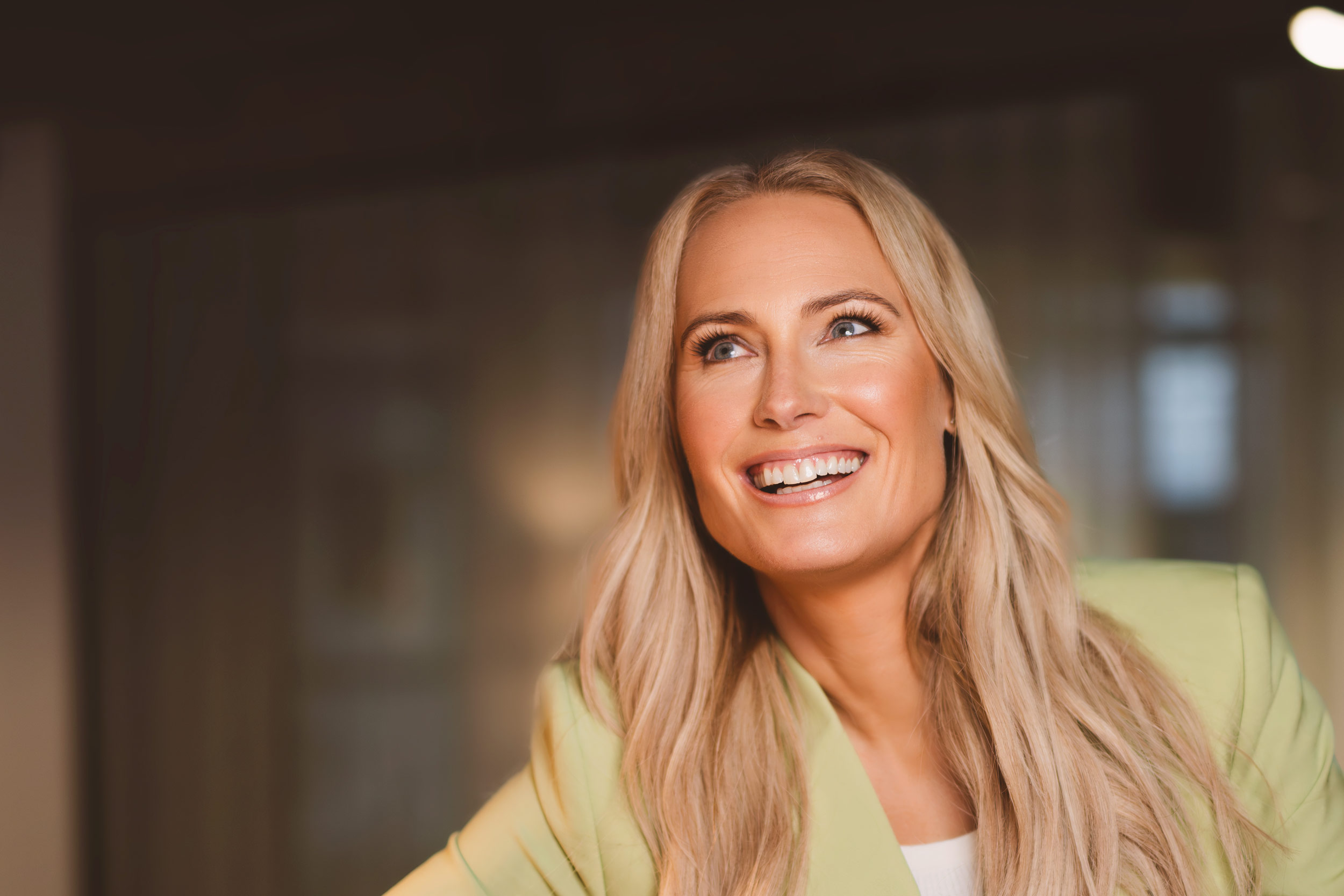 Närbild på Jennie Brobeck med ett stort varmt leende och självsäker blick, mjukt ljus och inbjudande känsla.