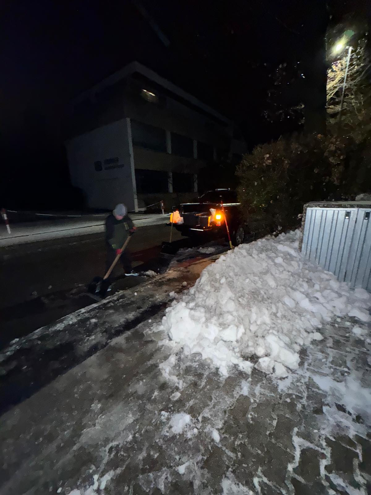 Person in a plaid shirt reaching for orange-handled pruning shears on a white countertop next to a black toolbox filled with tools.